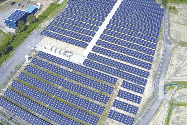 太陽光発電所の空撮。広大な敷地に、たくさんの太陽光パネルが並んでいる。